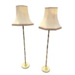 A pair of brass standard lamps, the baluster ringed columns on circular weighted saucer moulded