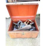 A domed top tin trunk with brass lock, having handles to ends, containing a quantity of hand tools -