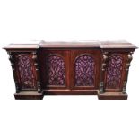 A Victorian rosewood breakfront cabinet with moulded top above arched fretwork doors enclosing