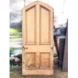 A large Victorian gothic shaped pine door, with four bollection moulded panels. (89in x 37.75in)