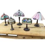 Five tablelamps with leaded glass colourful shades, raised on embossed faux brass patinated