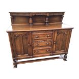 A carved oak sideboard, the back with plate shelf above a fluted apron supported on carved