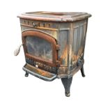 A cast iron wood burning stove with panelled top and sides, having arched glazed door above a