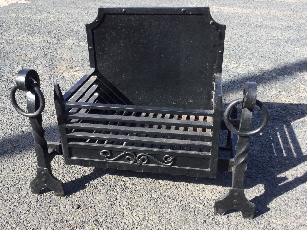 An C18th style cast iron firegrate, with panelled fireback and basket grate supported on fire dogs