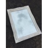 A rectangular bevelled mirror in white painted scrolled frame having inner beaded border. (35.75in x