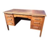 An oak kneehole desk with rectangular top above a kneehole flanked by pedestals, each with three