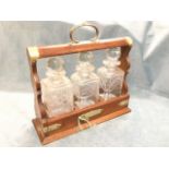 An oak tantalus with silver plated mounts, the locking box with three square cut glass decanters