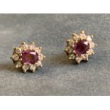 A pair of 18ct gold oval ruby earrings, each claw set stone framed by ten small diamonds, with