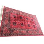 A Belouchi silk woven carpet with red field having eight medallions framed by floral borders