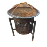 A garden brazier with circular grill burning chamber on three legs, with an associated cooking
