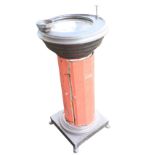 A plated metal drinking fountain with bowl and pump on a chamfered column fitted with a door