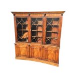 A reproduction concave fronted mahogany bookcase with moulded dentil cornice on scroll carved