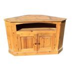 A pine corner cupboard with moulded top above open compartment and fielded panelled doors, raised on