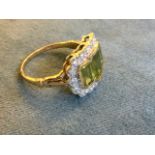 A 9 carat gold ring bezel set with three baguette cut peridots framed by a border of small