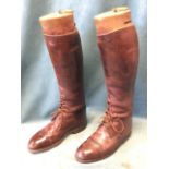 A pair of lace-up brown leather hunting boots with hardwood trees mounted with brass rings, by