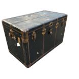 A rectangular Edwardian cabin trunk with brass mounts having studded strap bindings, with leather