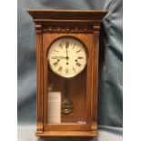 A mahogany cased Vienna style wallclock by Howard Miller, with moulded cornice above an arched