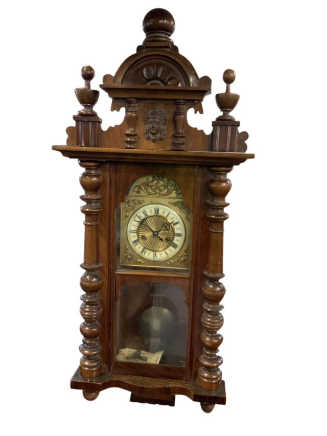 A Victorian walnut Vienna wallclock with arched carved crest flanked by turned finials having