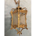 A hexagonal hanging brass hall lantern with star cut glass panels in scrolled frames, supported by