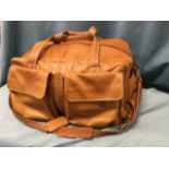 A large leather hold-all by Tula, the bag with numerous pockets and shoulder strap, having brass
