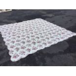 A large floral cotton quilt printed with pink flowers on cream ground, with scalloped edge. (103in x