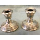 A pair of hallmarked silver dwarf candlesticks with urn shaped candleholders on circular ribbed