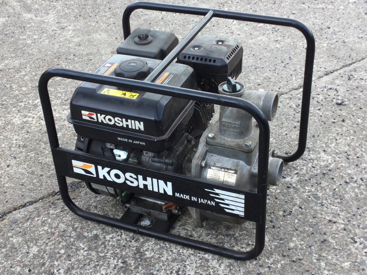 A portable Koshin hidels pump with petrol engine on tubular frame/stand.