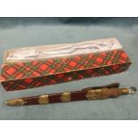 A boxed Scottish imitation dirk, the leather sheath with brass thistle mounts having carved wood