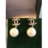 A pair of 925 hallmarked silver faux pearl drop earrings, with balls hung from crossed Cs, fitted