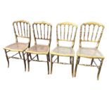 A set of four late Victorian gilded side chairs with shaped backs on turned spindles above cane