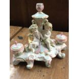 A Meissen style continental porcelain inkstand with central candlestick supported by putti flanked