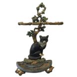 A cast iron stickstand with tree supporting twin twig framed apertures above a cat, having semi-