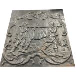An antique cast iron fireback with panel depicting two medieval style figures carrying a deer in