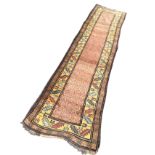 An Afghan style wool runner with pink honeycomb field on fawn ground framed by band of serrated leaf
