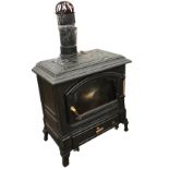 A cast iron wood burning stove with moulded rectangular top above an arched glazed door with ash