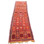 A Moroccan runner woven with bright rectangular panels of geometric motifs, figures and camels on