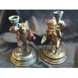 A pair of cold painted bronze fox and bear candlesticks, both modelled with raised glasses, the