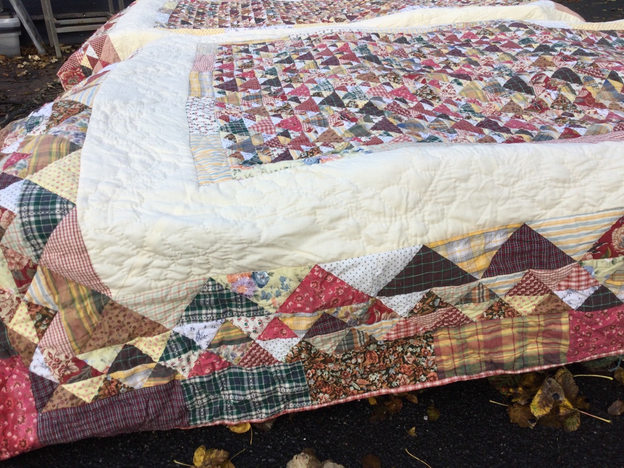 A pair of cotton quilts, the central panels with multi patterned triangles framed by a border of - Image 2 of 3