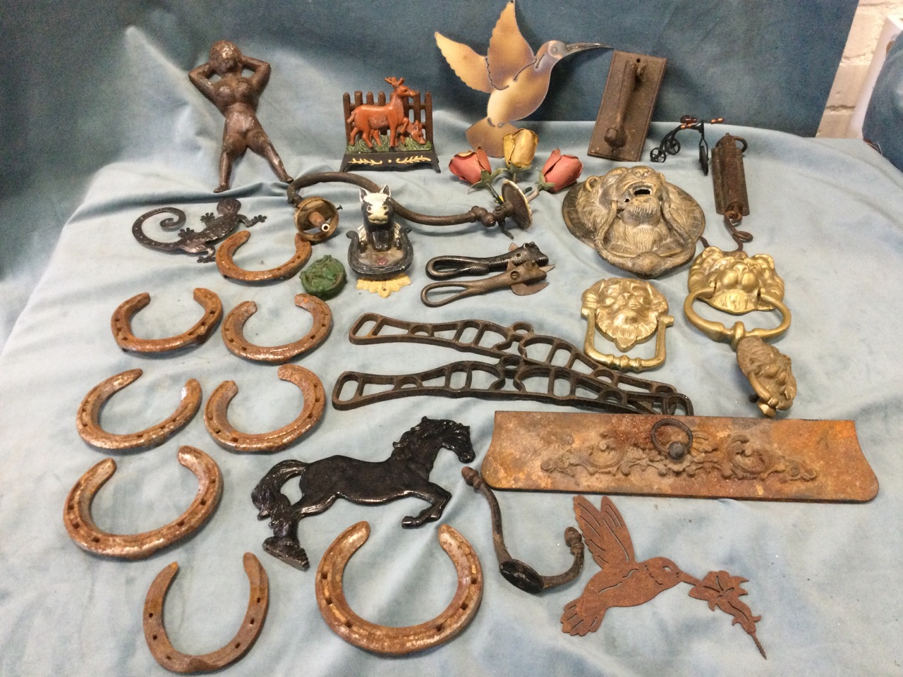 Miscellaneous metalware including four lionmask door knockers, a cast iron figure, horseshoes, pegs,