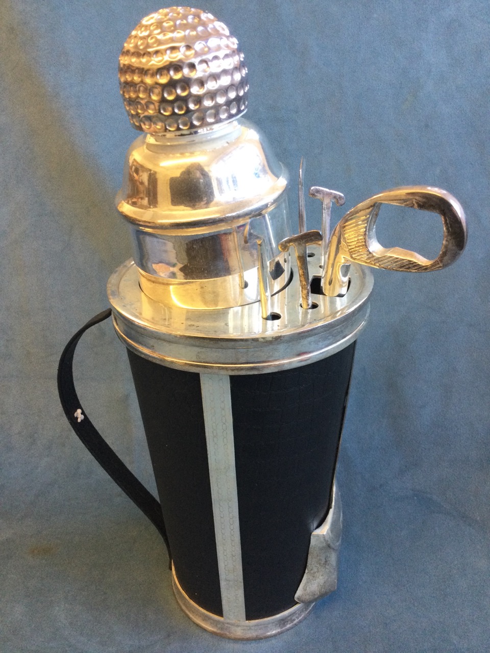 A silver plated golf cocktail shaker on stand, the vessel with golf ball cover on a base modelled as