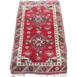 A Turkish rug woven with two spider type medallions with hooked borders on red floral field,