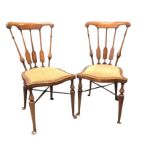 A pair of art nouveau Edwardian chairs with shaped back rails on turned and flattened spindles,