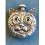 A sterling silver scent bottle embossed and modelled as a cats head with inlaid glass eyes, having