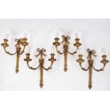 Set of four brass two branch wall lights with ribbon and lion mask decoration
