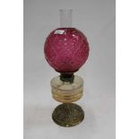 Edwardian oil lamp with cranberry glass shade, cut glass reservoir on embossed brass base