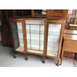 1930s walnut veneered display cabinet enclosed by three glazed doors with bowed glass panels on cabr