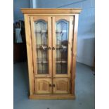 Contemporary stained pine bookcase with two leaded glazed doors above enclosing three fixed shelves