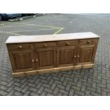 Pine sideboard with four drawers and cupboards below enclosed by four panelled doors on plinth base,