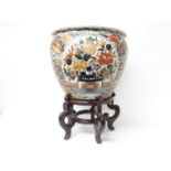 Large pair of Japanese Imari fishbowls on wooden stands, painted with flowers and birds, with goldfi