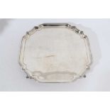 George V silver salver of square form, with pie crust decoration to corners, raised on four hoof fee